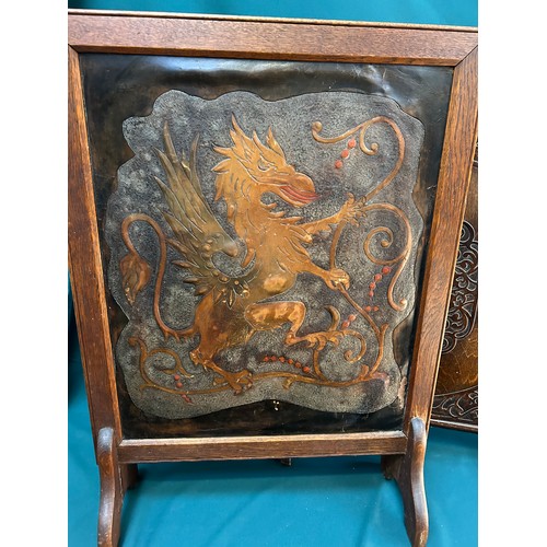 327A - Two 1920's /30's oak framed fire screens, one with embossed leather heraldic panel depicting a griff... 