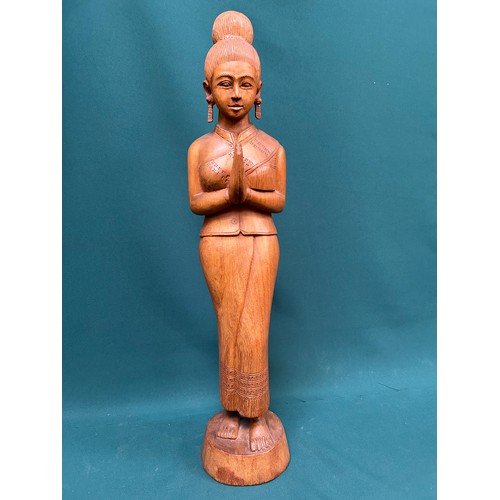 134 - A tall Balinese hand carved wooden figure of a woman in traditional dress. 60cm