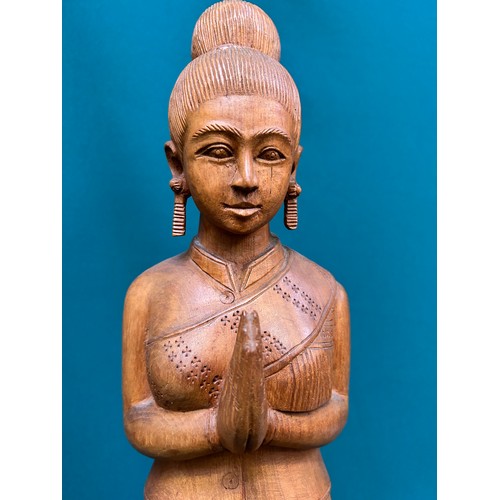 134 - A tall Balinese hand carved wooden figure of a woman in traditional dress. 60cm