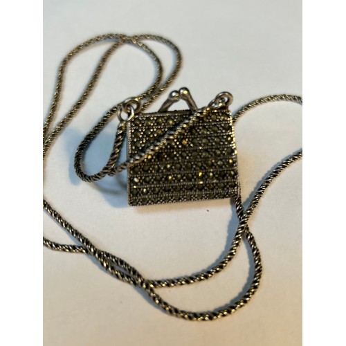 31 - A vintage sterling silver and marcasite handbag pendant / coin purse. The handbag with red stone cla... 