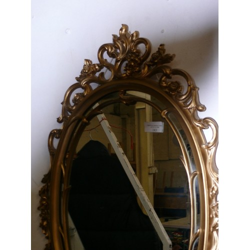 183 - AN ORNATE OVAL GILT FRAMED WALL MIRROR