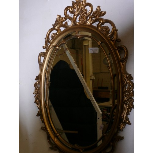 183 - AN ORNATE OVAL GILT FRAMED WALL MIRROR