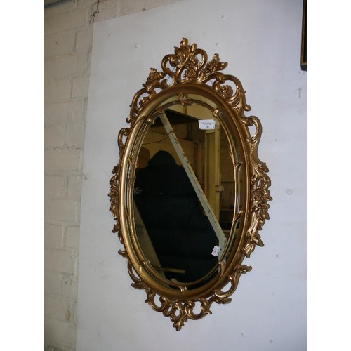 183 - AN ORNATE OVAL GILT FRAMED WALL MIRROR