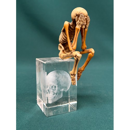 266 - A 3D Crystal Skull paperweight and a signed miniature seated skeleton.