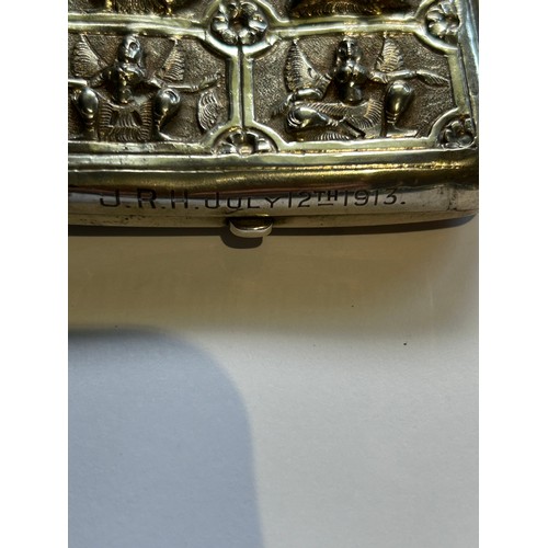 111A - An early 20th Century Burmese silver metal cigarette case with raised design of religious deities. E... 