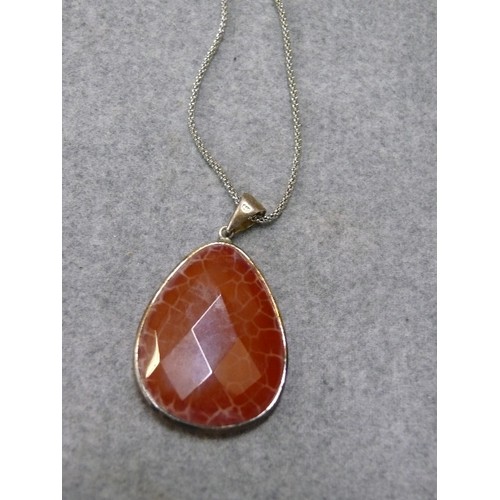 45 - A LARGE HEAVY SILVER PENDANT WITH A LOVELY ORANGE CARNELIAN CRYSTAL STONE ON A 27 INCH SILVER CHAIN