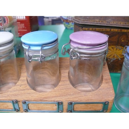 302 - A VINTAGE SPICE SET WITH JARS WITH COLOURED LIDS IN A WOODEN RACK