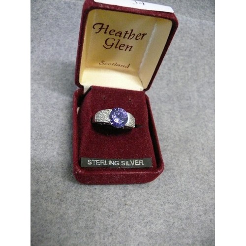 34 - A SOLID SILVER RING WITH A LARGE LIGHT PURPLE STONE SIZE Q