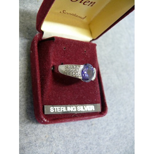 34 - A SOLID SILVER RING WITH A LARGE LIGHT PURPLE STONE SIZE Q