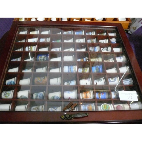 142 - A LARGE COLLECTION OF CERAMIC THIMBLES AND BELLS IN WOODEN DISPLAY CASES