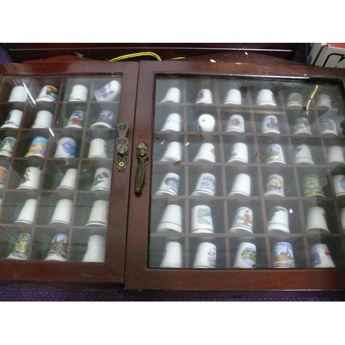 142 - A LARGE COLLECTION OF CERAMIC THIMBLES AND BELLS IN WOODEN DISPLAY CASES