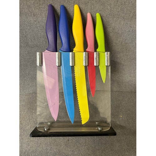 465 - A SET OF COLOURFUL KITCHEN KNIVES IN A CLEAR STAND