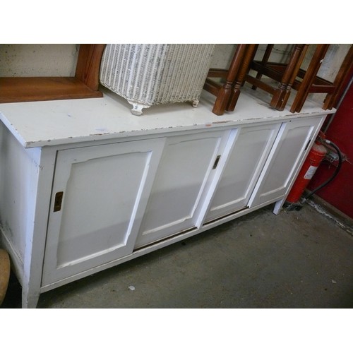 268 - A LONG VINTAGE WHITE PAINTED SIDEBOARD WITH SLIDING PANELLED DOORS.