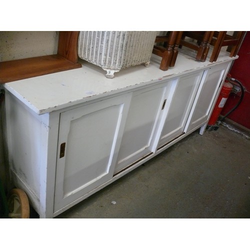 268 - A LONG VINTAGE WHITE PAINTED SIDEBOARD WITH SLIDING PANELLED DOORS.