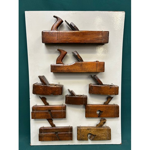 383 - Display board with collection of vintage carpenters planes including smoothing planes, moulding plan... 