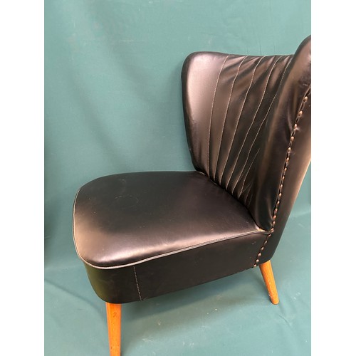 489 - An original 1950’s cocktail chair in black leather upholstery with curved wing back, on splayed tape... 