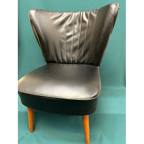 489 - An original 1950’s cocktail chair in black leather upholstery with curved wing back, on splayed tape... 