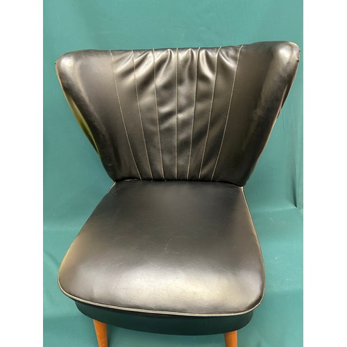 489 - An original 1950’s cocktail chair in black leather upholstery with curved wing back, on splayed tape... 