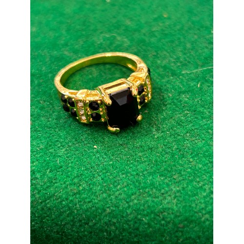 12 - DESIGNER GILT METAL RING WITH BLACK CRYSTAL STONES AND DIAMANTE - SIZE V