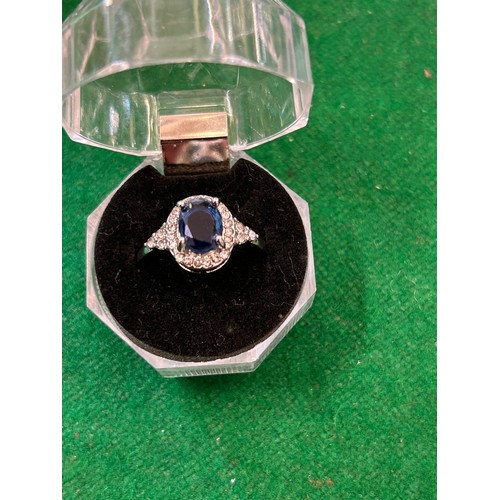 14 - STYLISH SILVER METAL RING SET WITH LARGE OVAL SAPPHIRE COLOURED STONE SURROUNDED BY DIAMANTE - SIZE ... 