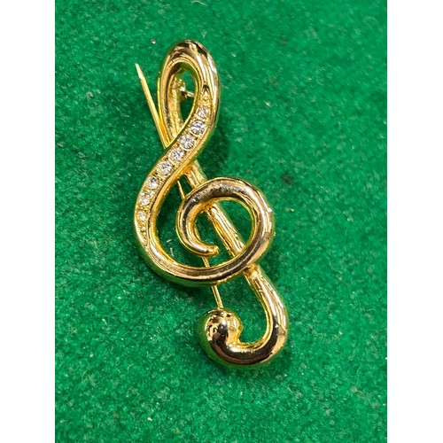 41 - TWO BROOCHES INCLUDING A TREBLE CLEF MUSIC NOTE AND A HAND & HEART BROOCH WITH EMERALD COLOUR & CLEA... 