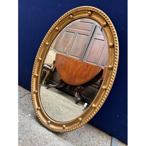 429 - Regency style oval mirror, bevel edged, the gilt frame with gadrooning & ball decoration. 80cm x 52c... 