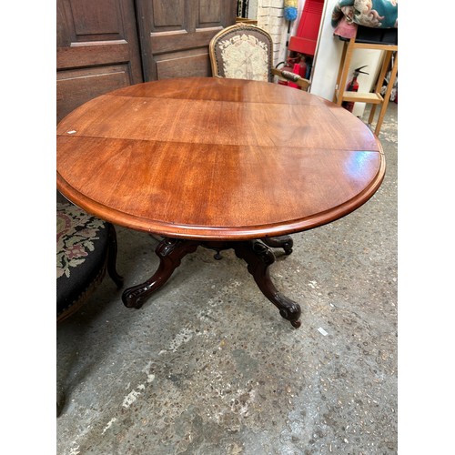 423 - Victorian mahogany drop leaf table on turned pedestal with four splayed carved legs with pot castors... 