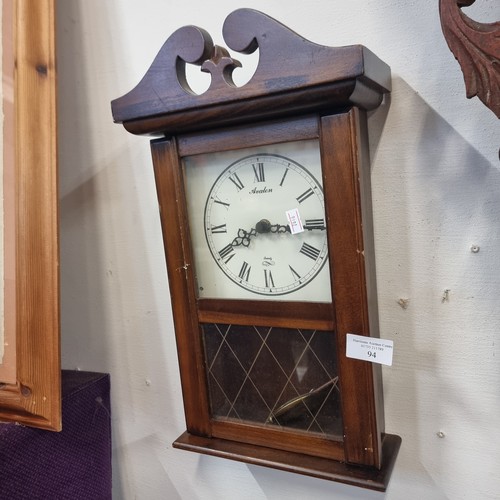 94 - A SMALL AVALON WALL CLOCK IN NICE WOODEN CASE WITH ROMAN NUMERALS IN A CREAM FACE WITH PENDULUM.