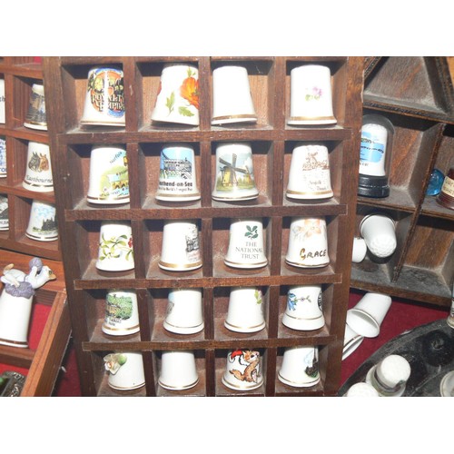 292 - LARGE COLECTION OF MOSTLY CERAMIC THIMBLES WITH DISPLAY CASES PLUS SOUVENIR SPOONS ON A WALL RACK