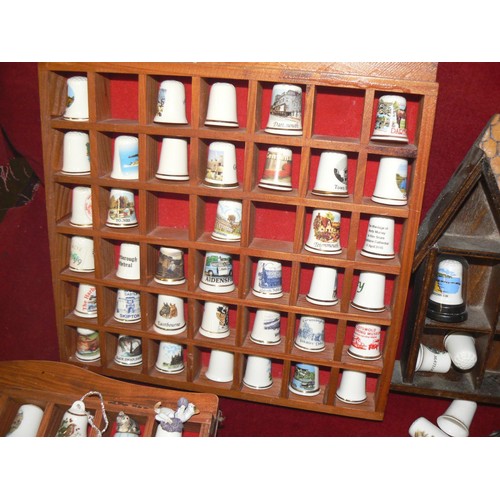 292 - LARGE COLECTION OF MOSTLY CERAMIC THIMBLES WITH DISPLAY CASES PLUS SOUVENIR SPOONS ON A WALL RACK