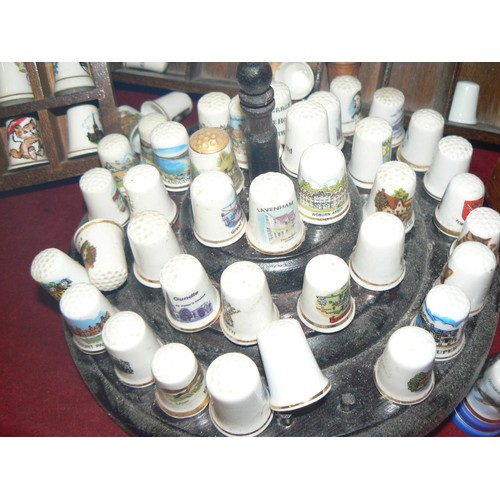 292 - LARGE COLECTION OF MOSTLY CERAMIC THIMBLES WITH DISPLAY CASES PLUS SOUVENIR SPOONS ON A WALL RACK