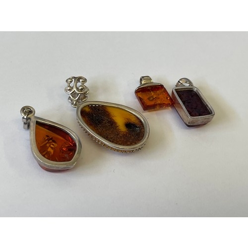 34 - A COLLECTION OF FOUR SOLID SILVER AND BALTIC AMBER PENDANTS