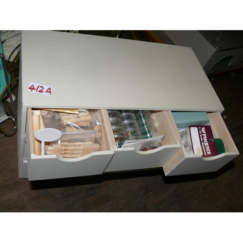 412A - A SMALL CREAM COLOURED CHEST WITH CONTENTS OF DOLLS HOUSE ITEMS - MOSTLY NEW & PACKAGED INCLUDING BR... 