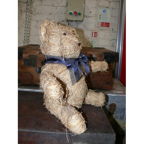 410 - A straw teddy bear wearing a blue ribbon. 35cm tall.