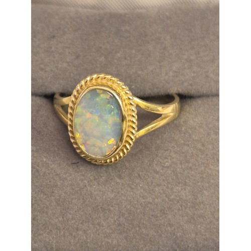 36 - An 18ct gold and opal dress ring, the oval opal showing good range of vibrant colours, 11.3 by 8.1mm... 