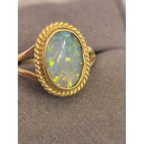 36 - An 18ct gold and opal dress ring, the oval opal showing good range of vibrant colours, 11.3 by 8.1mm... 