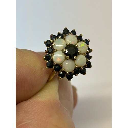 23 - A SAPPHIRE AND BLACK OPAL MULTI COLOURS 9ct GOLD FLOWER PATTERN WITH SAPPHIRE CENTRE AND ALL AROUND ... 