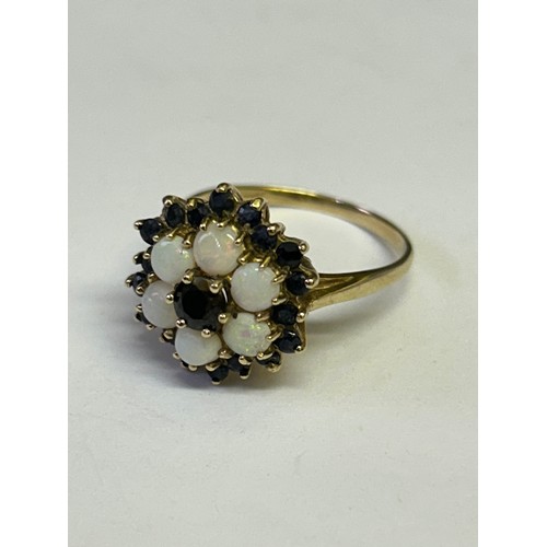 23 - A SAPPHIRE AND BLACK OPAL MULTI COLOURS 9ct GOLD FLOWER PATTERN WITH SAPPHIRE CENTRE AND ALL AROUND ... 