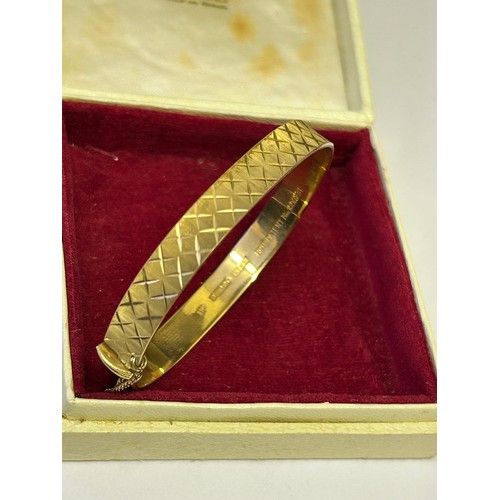 34 - A 9ct GOLD DESIGNER BANGLE BRACELET WITH SAFETY CHAIN ENGINE TURNED CROSS HATCH DESIGN WEIGHT 15.48g... 