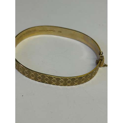 34 - A 9ct GOLD DESIGNER BANGLE BRACELET WITH SAFETY CHAIN ENGINE TURNED CROSS HATCH DESIGN WEIGHT 15.48g... 