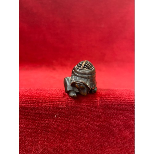 47 - Japanese boxwood Netsuke, finely carved in the form of a small figure crouching beneath a larger bōg... 