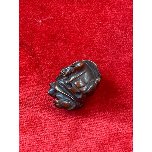 47 - Japanese boxwood Netsuke, finely carved in the form of a small figure crouching beneath a larger bōg... 