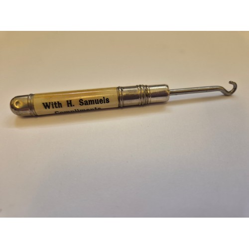 94B - Small advertising pocket button hook. White metal tube with screw action hook stored inside, the cel... 