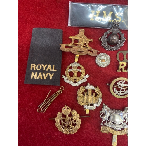 44 - Collection of military cap badges and naval ribbons/slides. Including army, marines and RAF brass ba... 