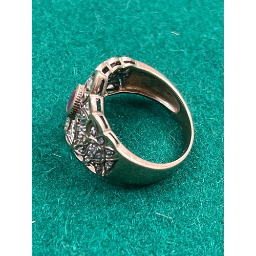 36 - A renaissance style 9ct gold ring set with a central oval cut  ruby surrounded by diamond chips in a... 