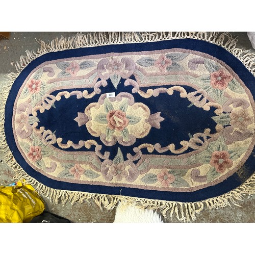 Blue oval floor rug with tasseled fringe plus a small white rug