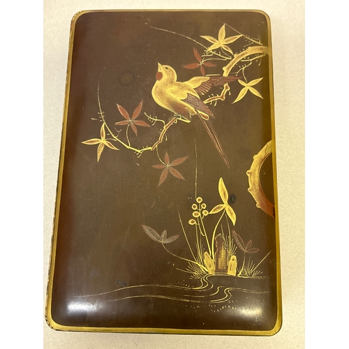 140 - An early 20th Century Japanese glove or scarf box in chestnut lacquer with gilt design of a bird on ... 