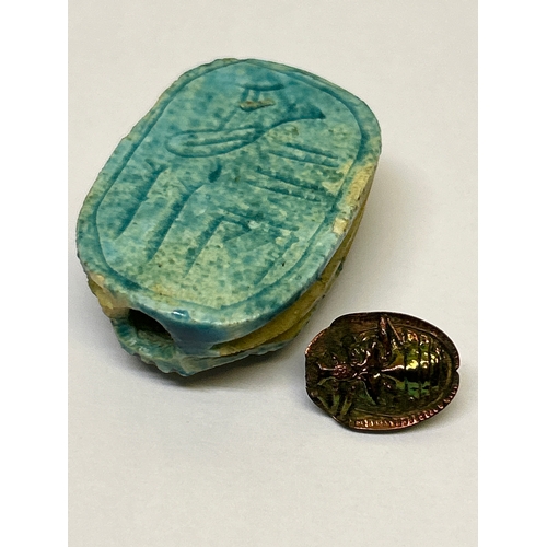 142 - Two scarab beetle pieces, one in ceramic with Egyptian Hieroglyphs, the other in patinated gilt meta... 