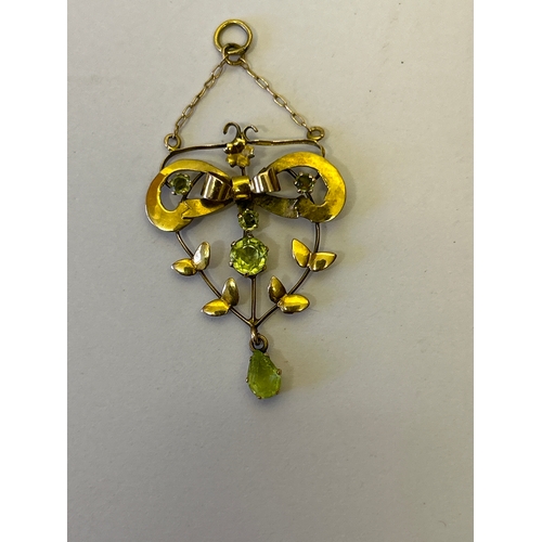 114 - An Edwardian 9ct gold lavalier pendant designed as a bow with leaf garland, set with  peridot stones... 