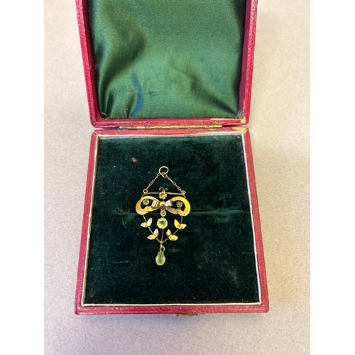 114 - An Edwardian 9ct gold lavalier pendant designed as a bow with leaf garland, set with  peridot stones... 